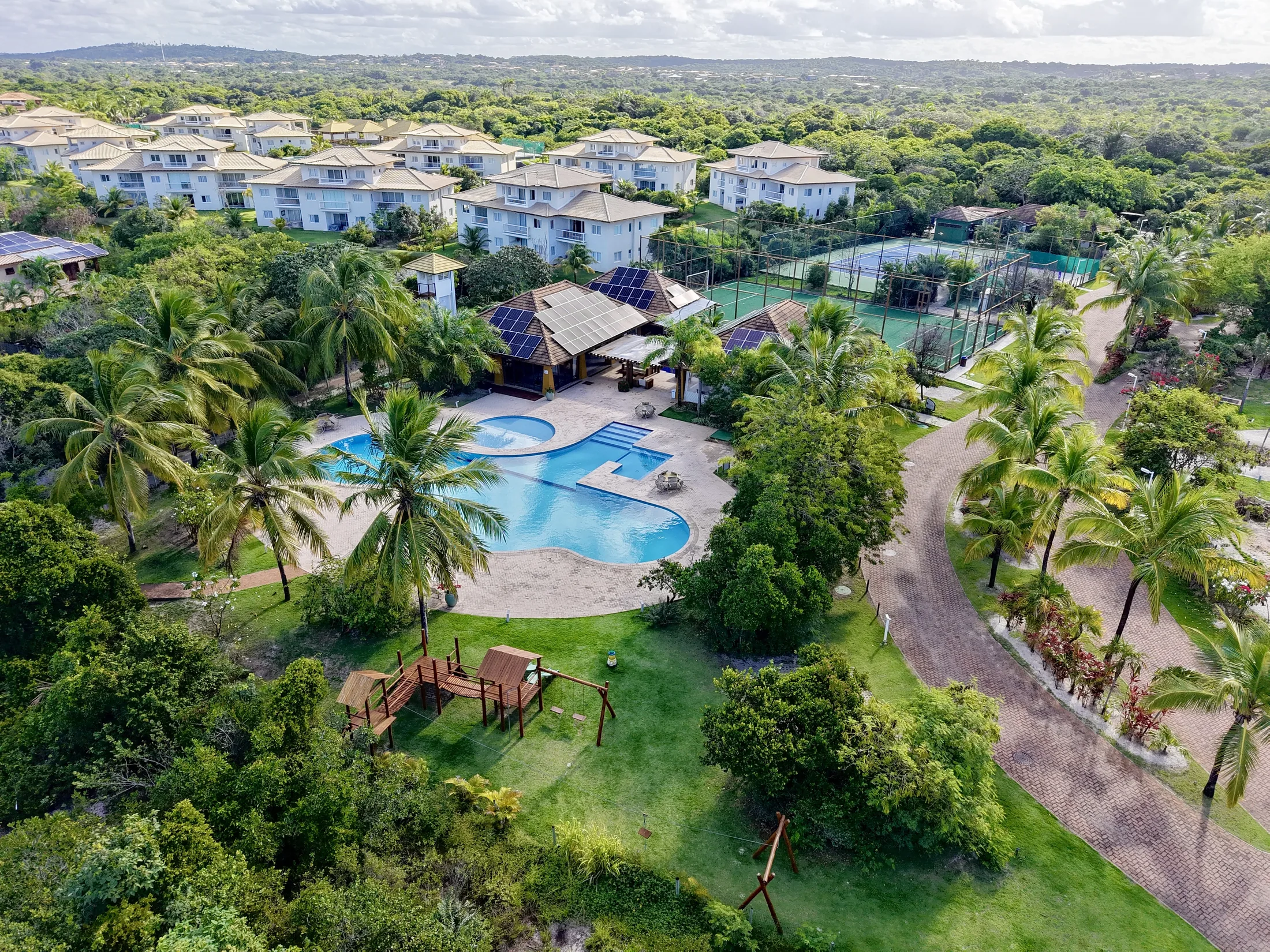 Vista aérea do condomínio, com casas, piscinas e o mar ao fundo