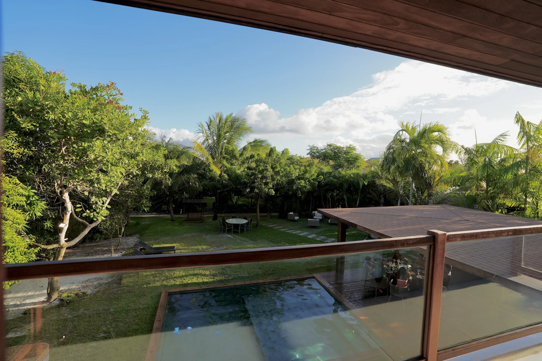 Varanda com guarda-corpo de vidro e vista para o jardim do condomínio