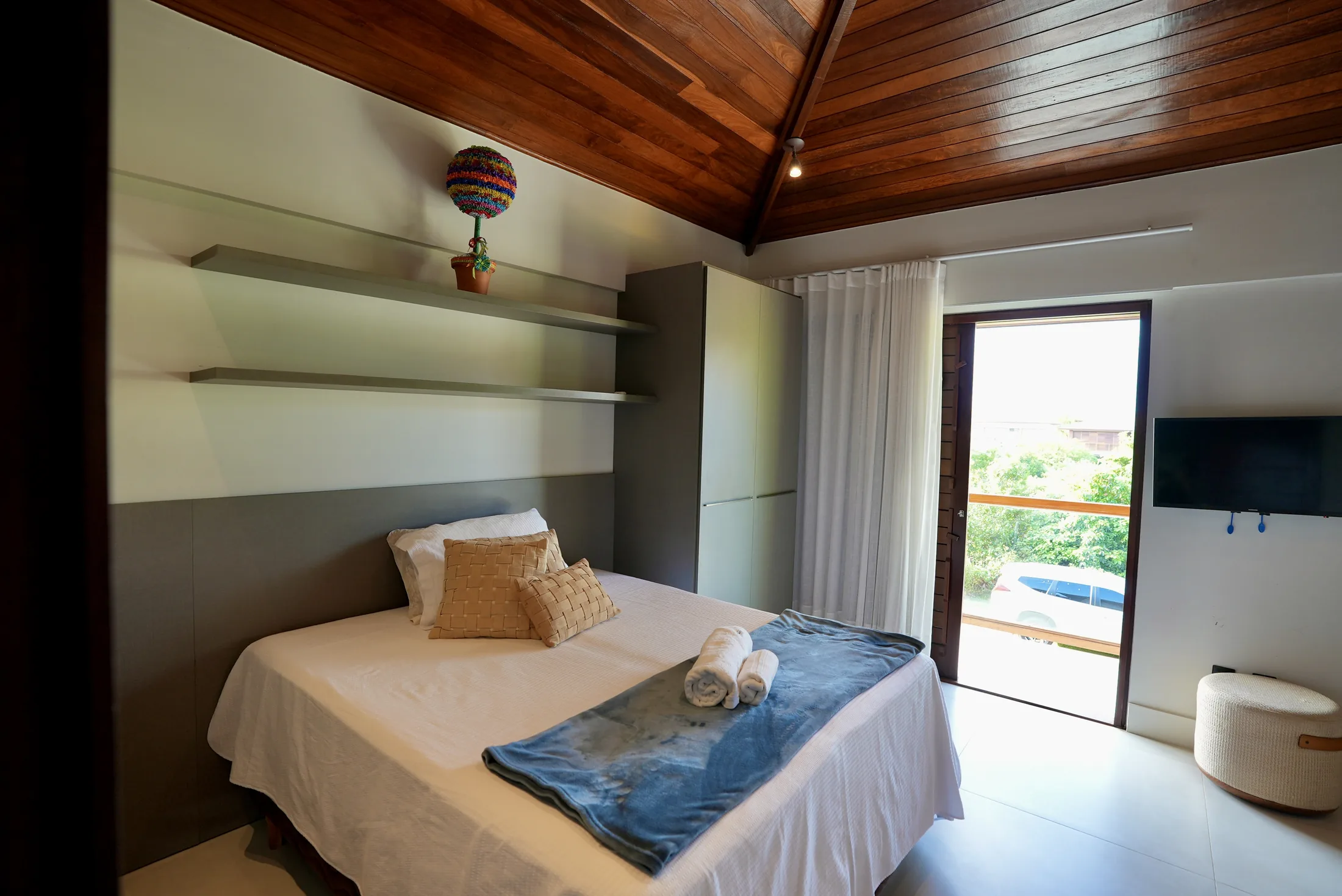 Suíte com cama de casal, TV e janela com vista para o mar